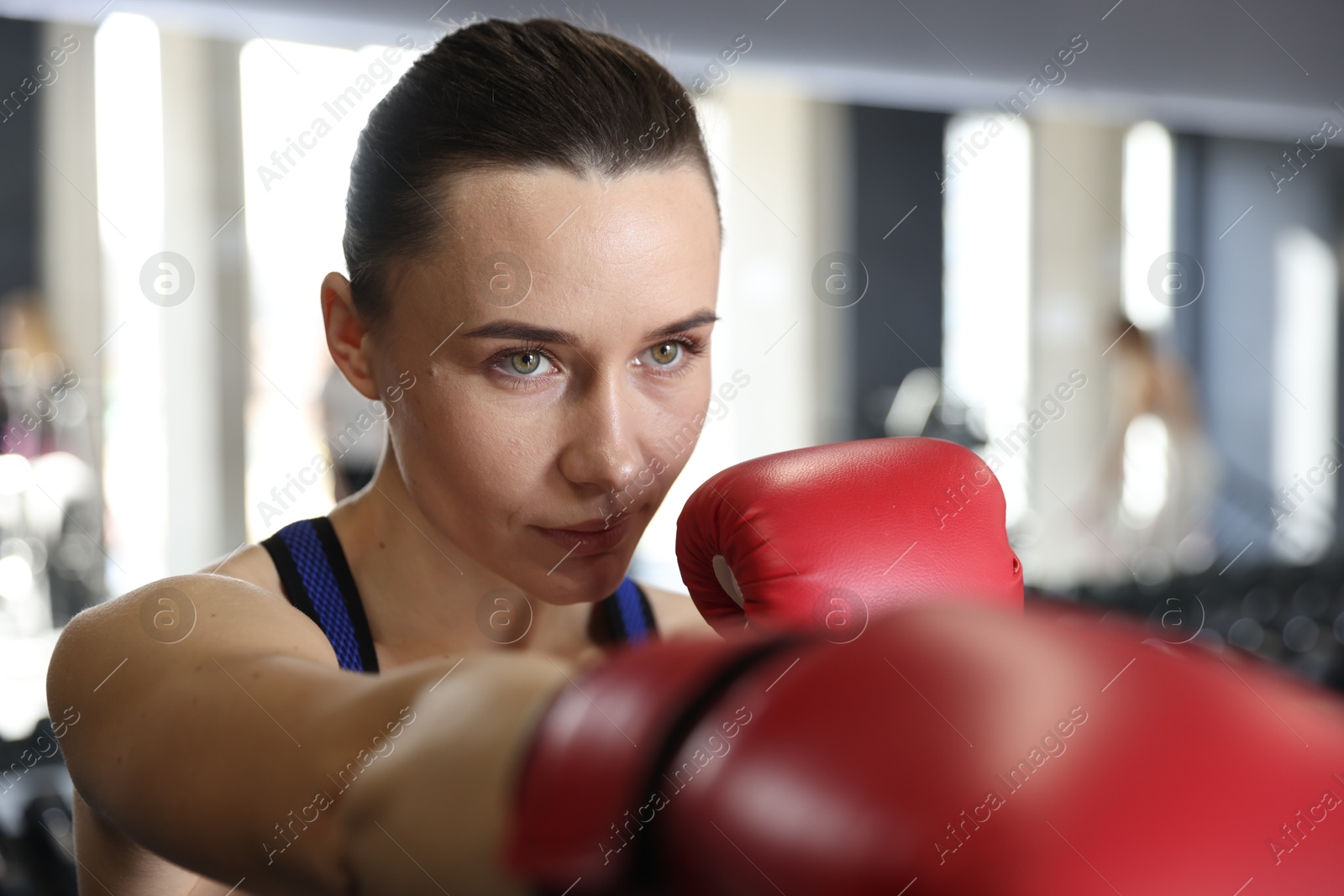 Photo of Woman wearing boxing gloves in gym, closeup