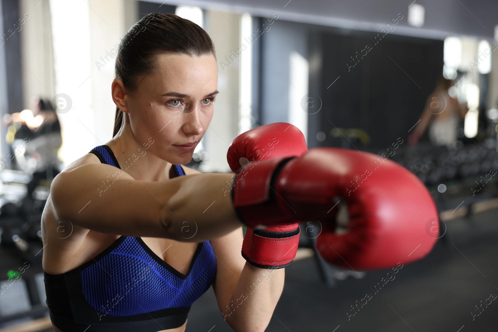 Photo of Athletic woman wearing boxing gloves training in gym