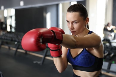 Photo of Athletic woman wearing boxing gloves training in gym