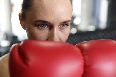 Photo of Woman wearing boxing gloves in gym, closeup