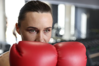 Photo of Woman wearing boxing gloves in gym, closeup