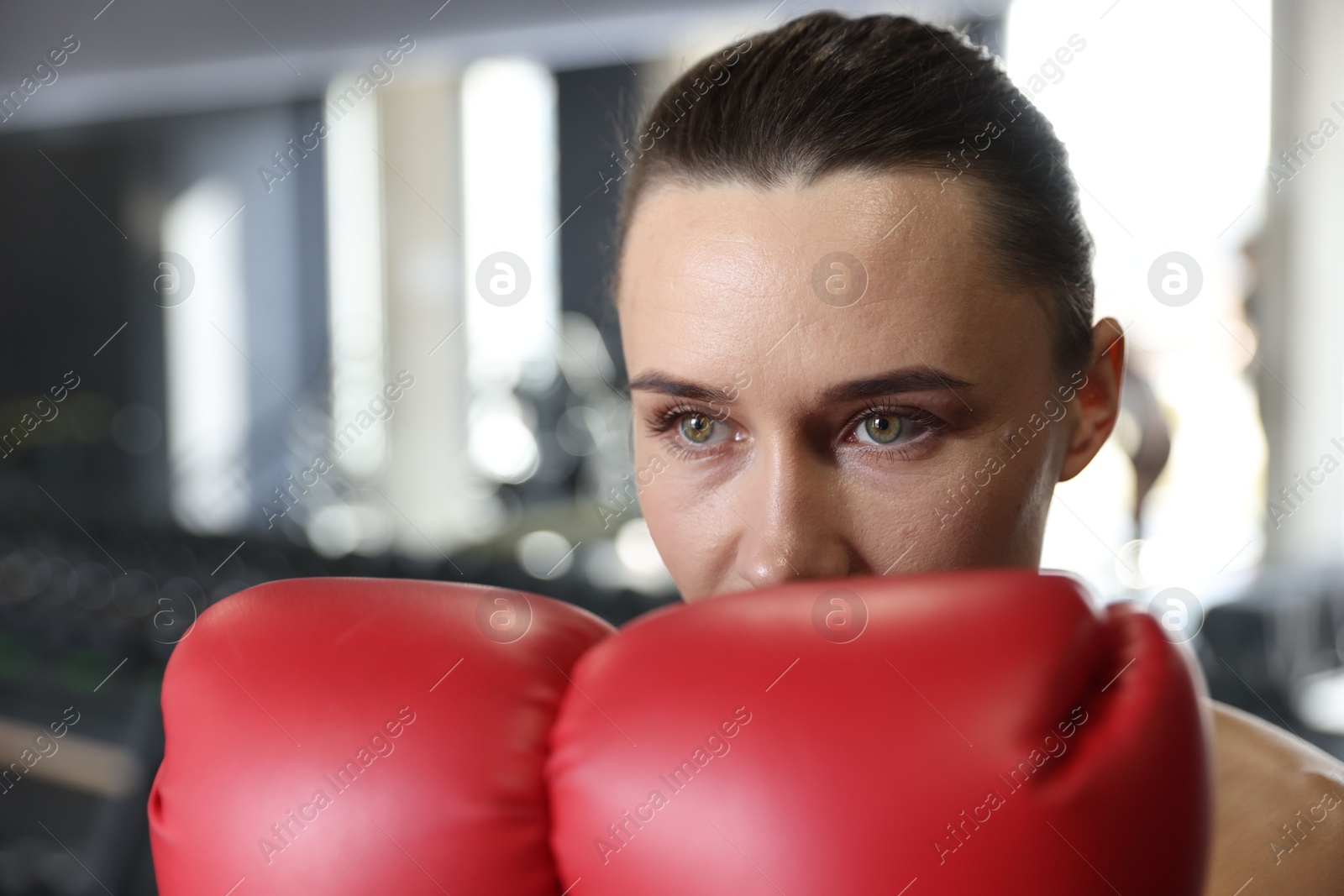 Photo of Woman wearing boxing gloves in gym, closeup