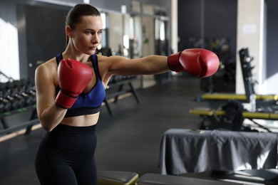 Photo of Athletic woman wearing boxing gloves training in gym