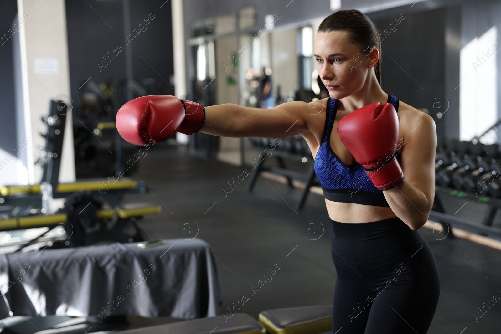 Photo of Athletic woman wearing boxing gloves training in gym