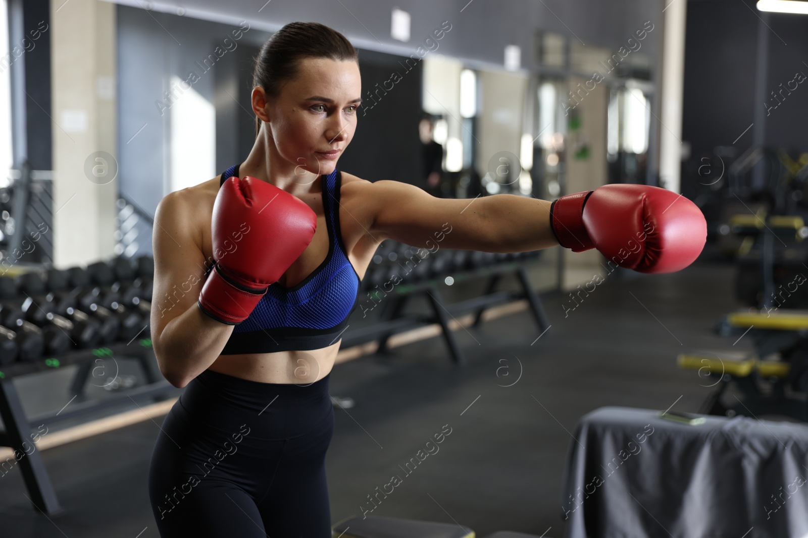 Photo of Athletic woman wearing boxing gloves training in gym