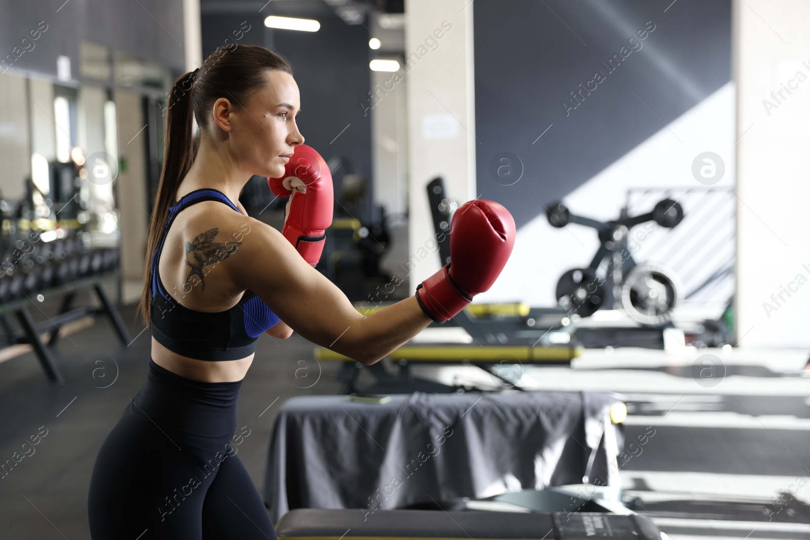 Photo of Athletic woman wearing boxing gloves training in gym. Space for text