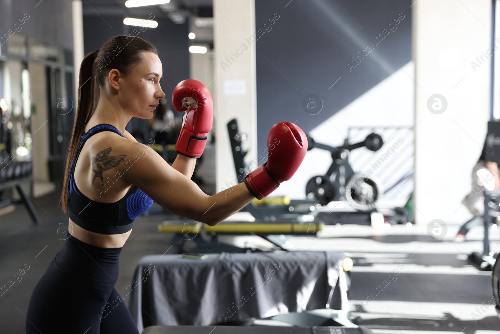 Photo of Athletic woman wearing boxing gloves training in gym. Space for text