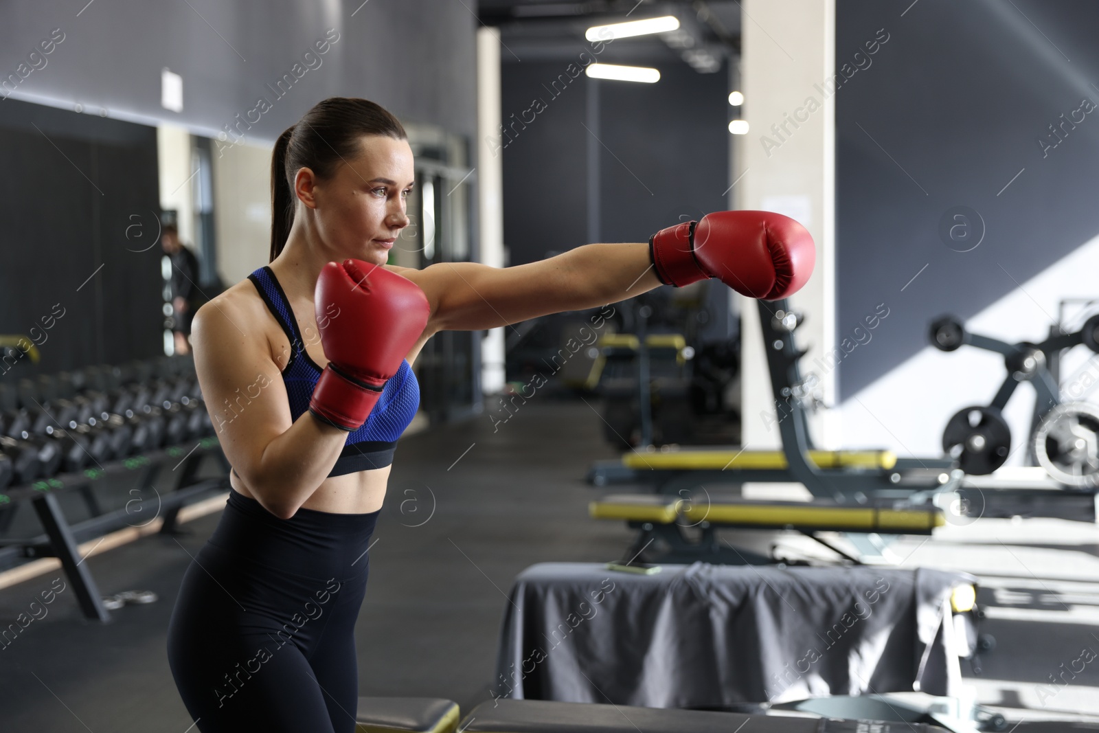 Photo of Athletic woman wearing boxing gloves training in gym