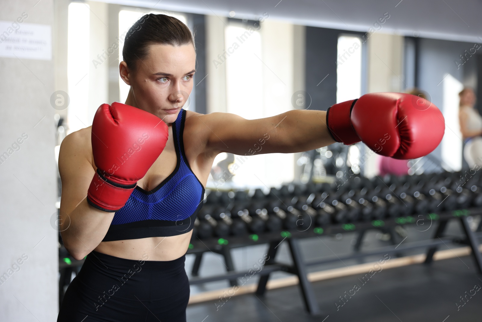 Photo of Athletic woman wearing boxing gloves training in gym