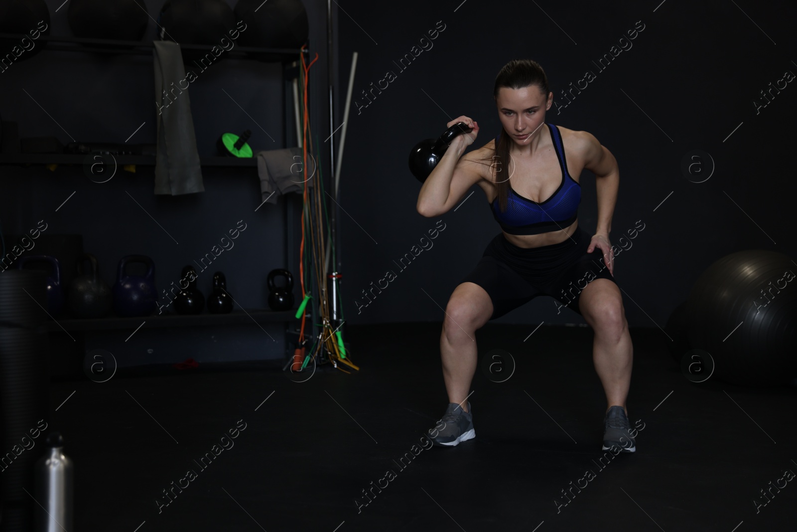 Photo of Athletic woman training with kettlebell in gym. Space for text