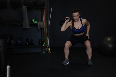 Athletic woman training with kettlebell in gym. Space for text