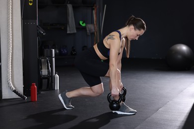 Photo of Athletic woman training with kettlebells in gym