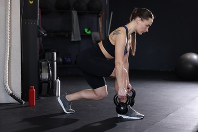 Photo of Athletic woman training with kettlebells in gym