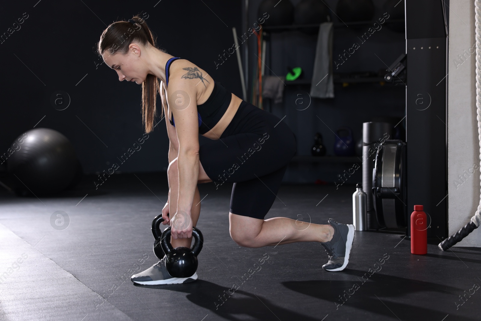 Photo of Athletic woman training with kettlebells in gym