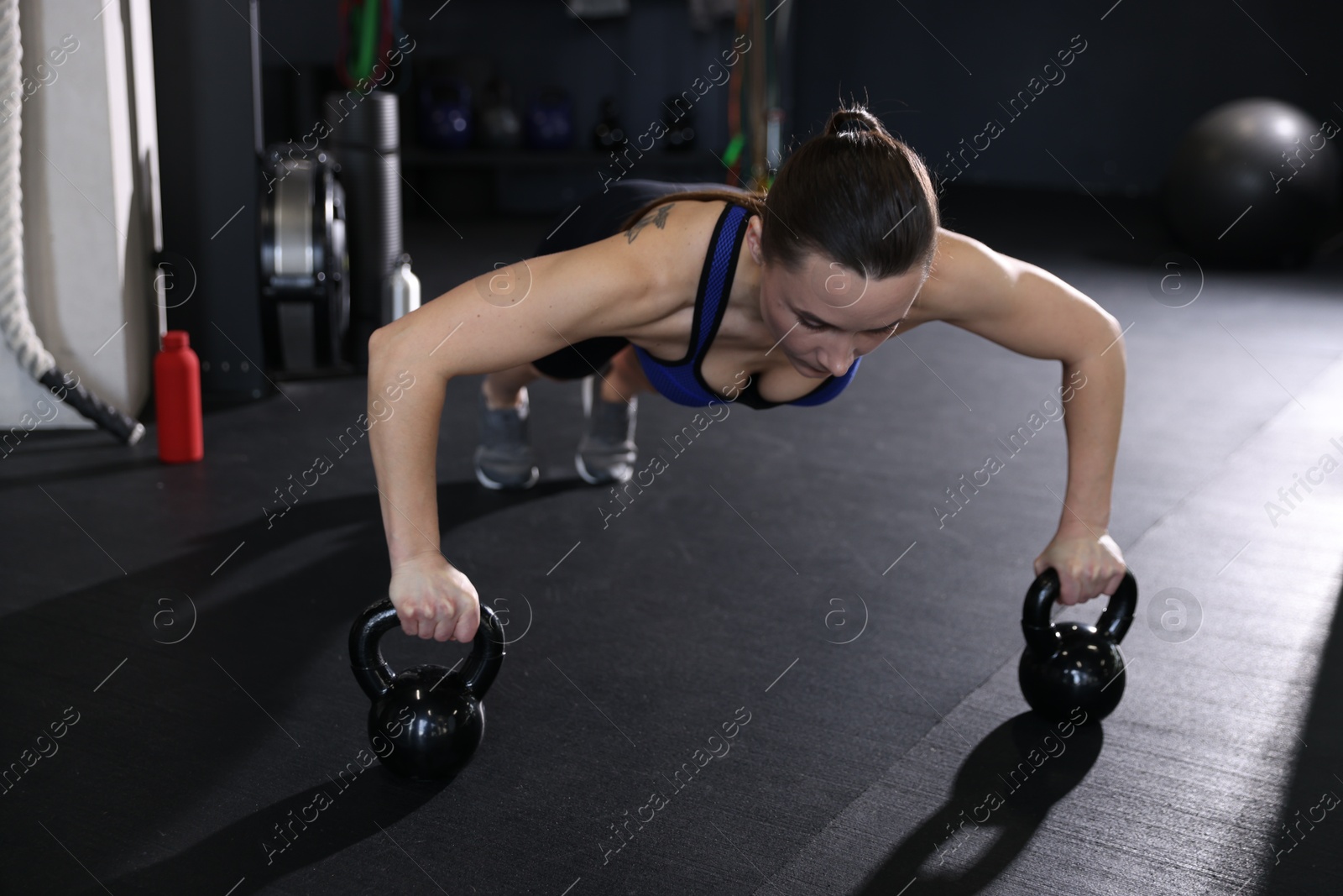 Photo of Athletic woman training with kettlebells in gym