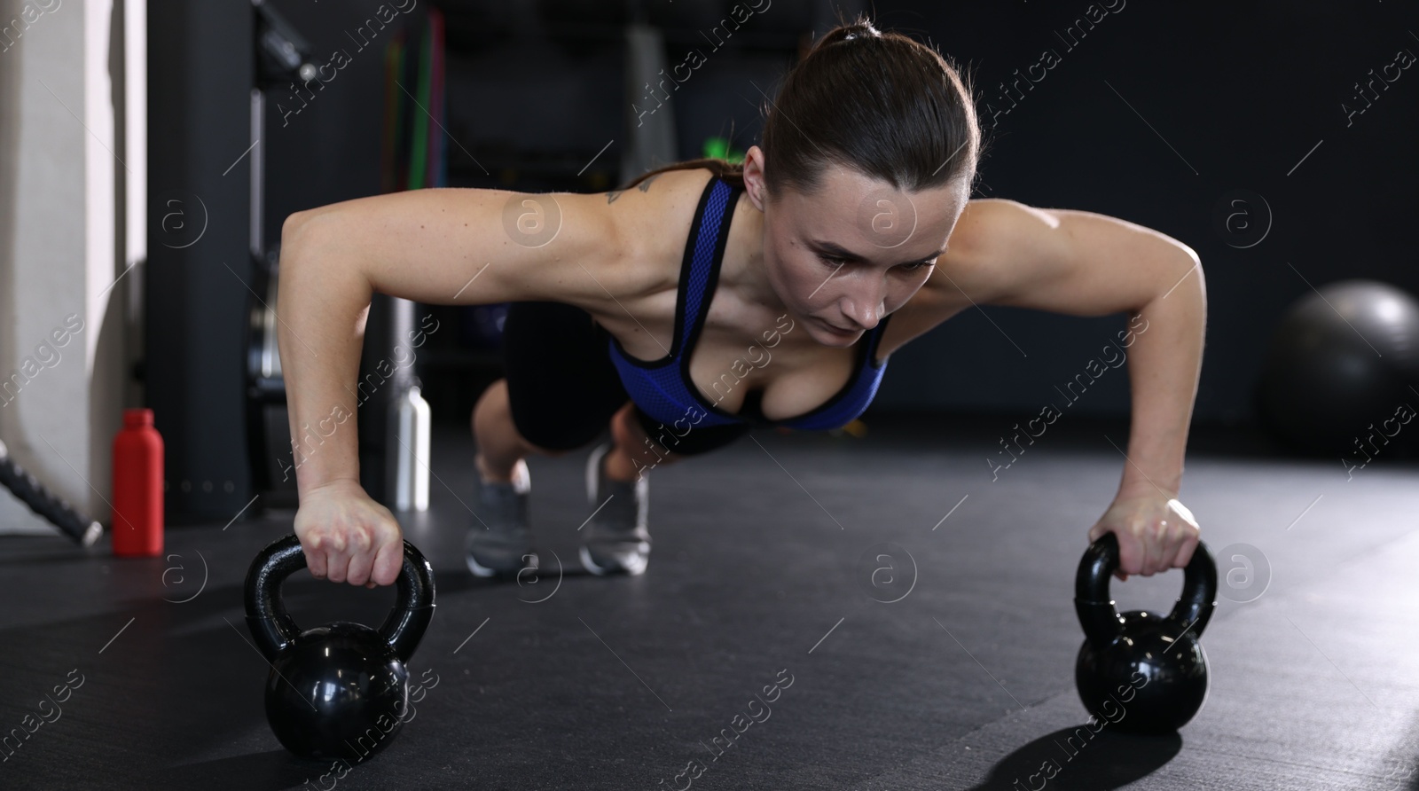 Photo of Athletic woman training with kettlebells in gym