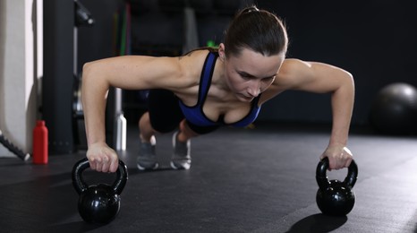 Athletic woman training with kettlebells in gym