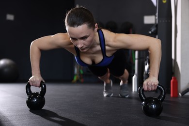 Athletic woman training with kettlebells in gym