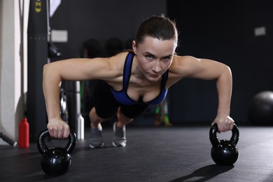 Athletic woman training with kettlebells in gym