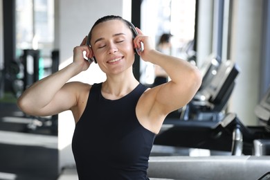 Smiling woman wearing headphones listening to music in gym