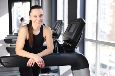 Portrait of smiling woman on treadmill in gym