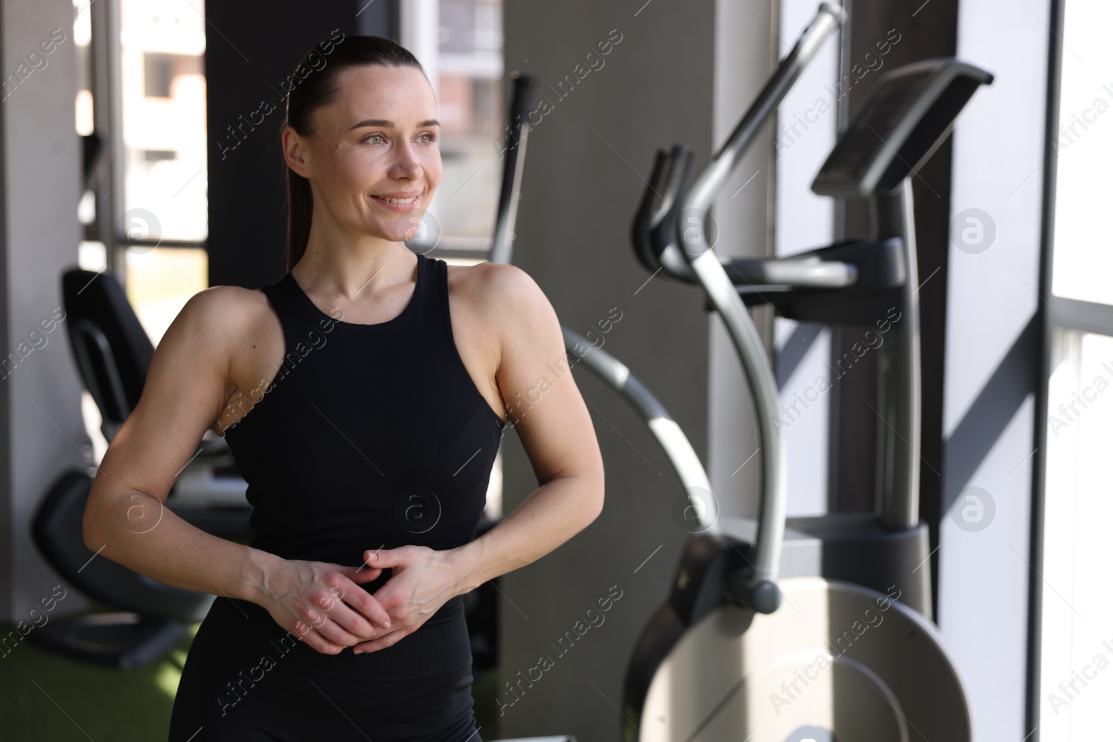 Photo of Portrait of smiling athletic woman in gym. Space for text