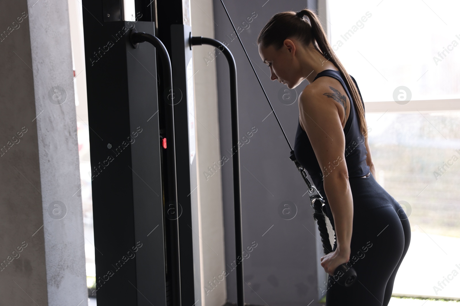 Photo of Athletic woman training on pulley machine in gym