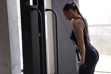 Athletic woman training on pulley machine in gym