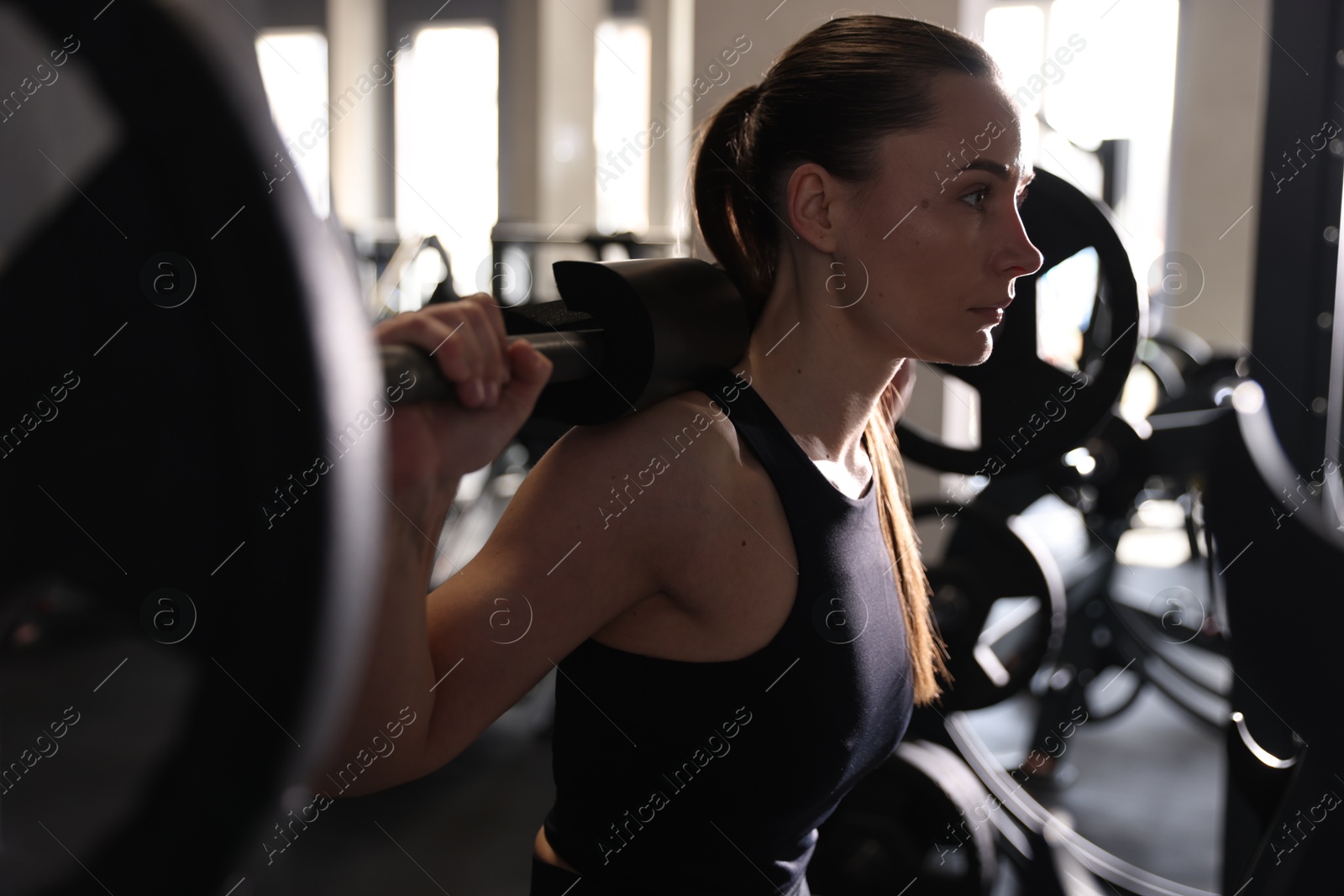 Photo of Athletic woman training with barbell in gym