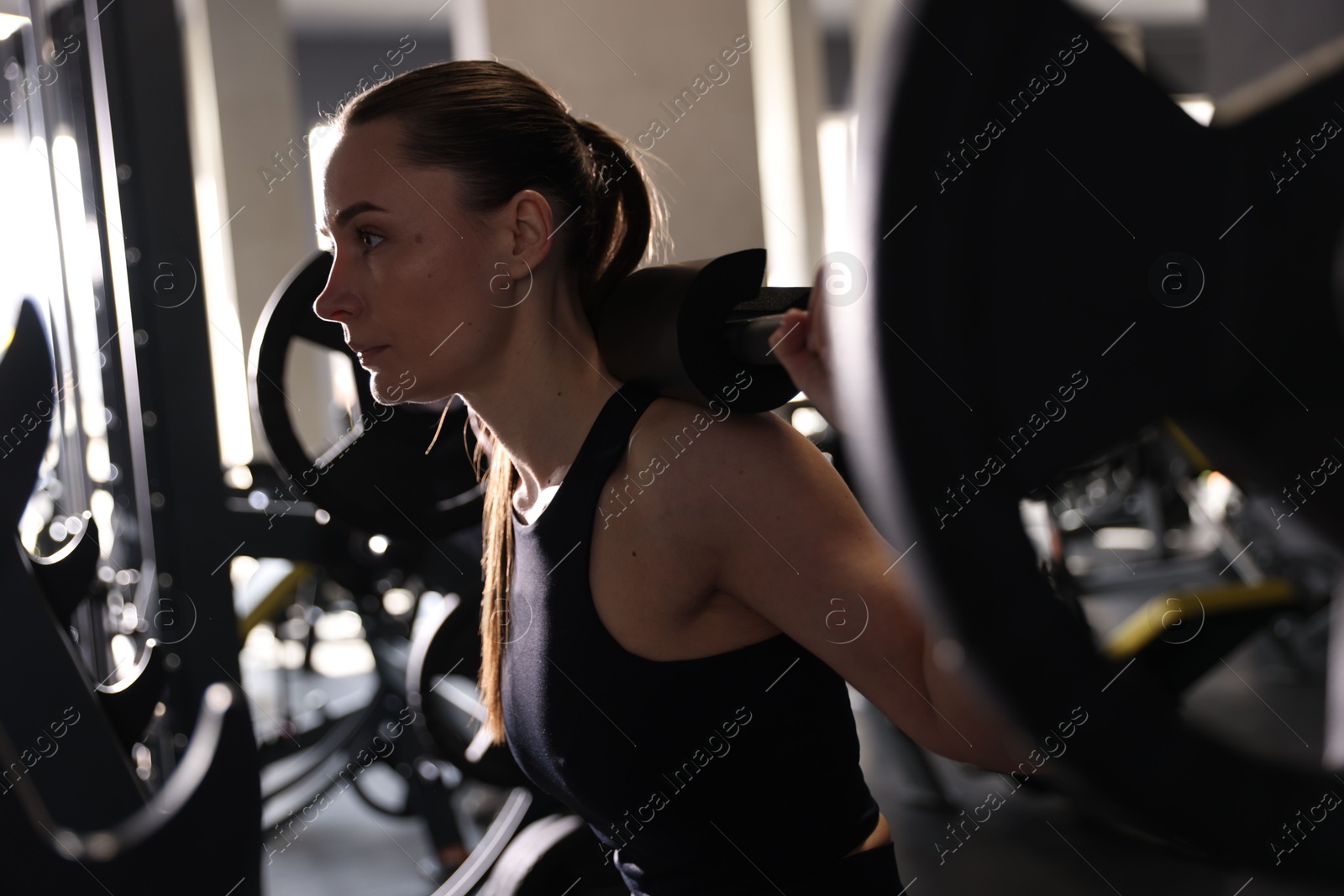 Photo of Athletic woman training with barbell in gym