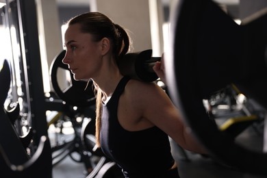 Athletic woman training with barbell in gym