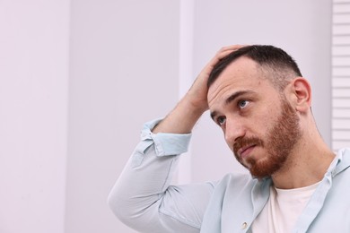 Photo of Baldness problem. Man with receding hairline in bathroom, space for text