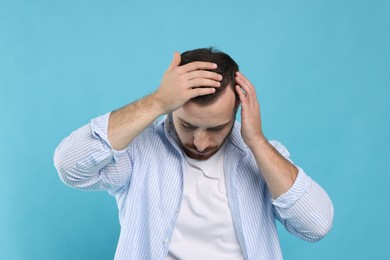 Baldness problem. Man with receding hairline on light blue background