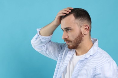 Baldness problem. Man with receding hairline on light blue background, space for text