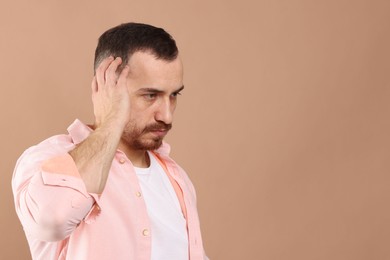 Baldness problem. Man with receding hairline on beige background, space for text