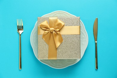 Beautiful table setting with romantic gift on light blue background, flat lay