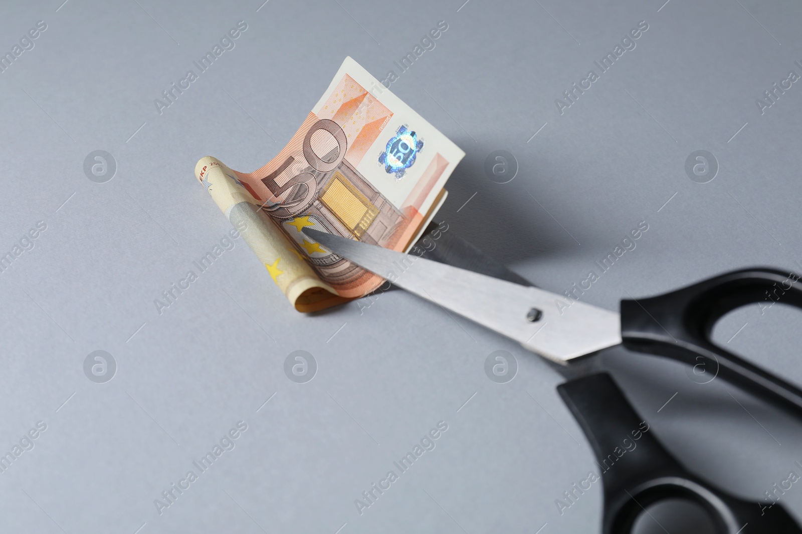 Photo of Scissors with euro banknote on gray background, closeup. Space for text