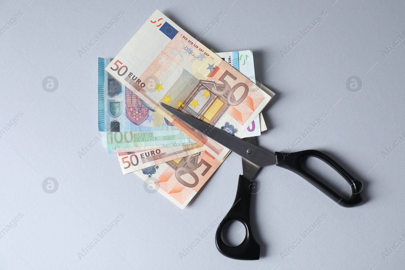 Photo of Euro banknotes and scissors on gray background, top view