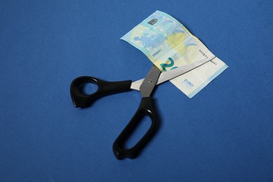 Photo of Scissors with euro banknote on blue background