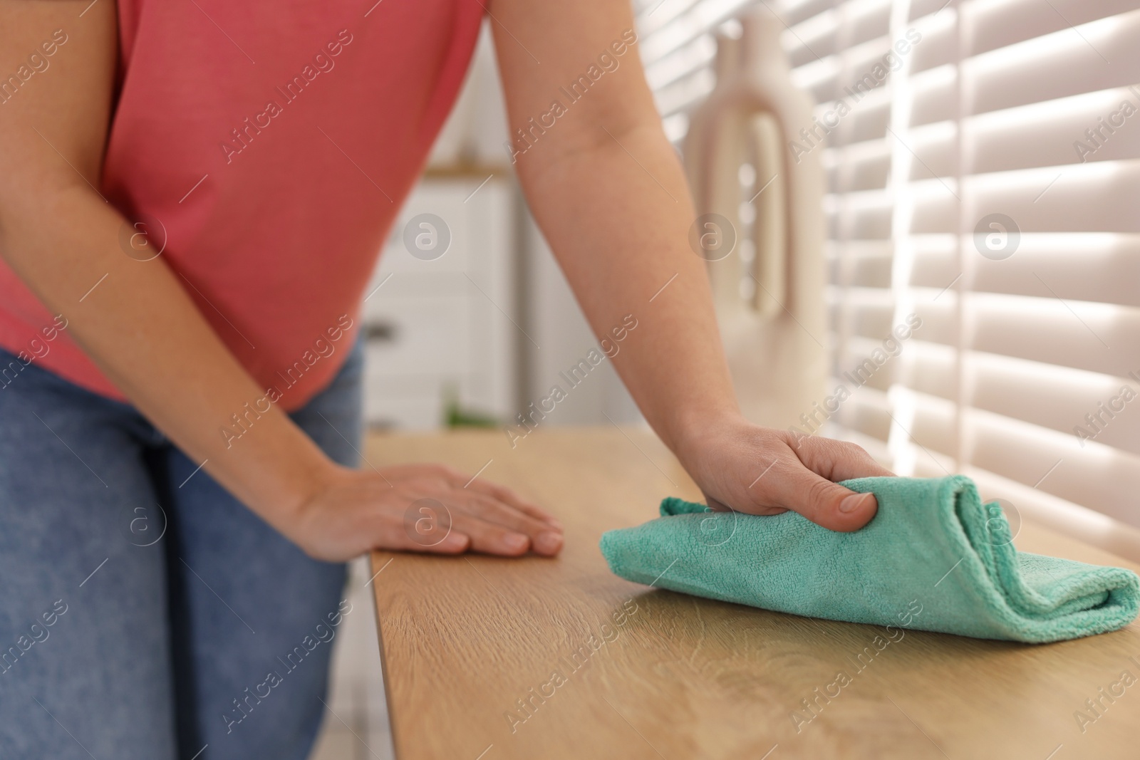 Photo of Woman polishing wooden table with rag at home, closeup