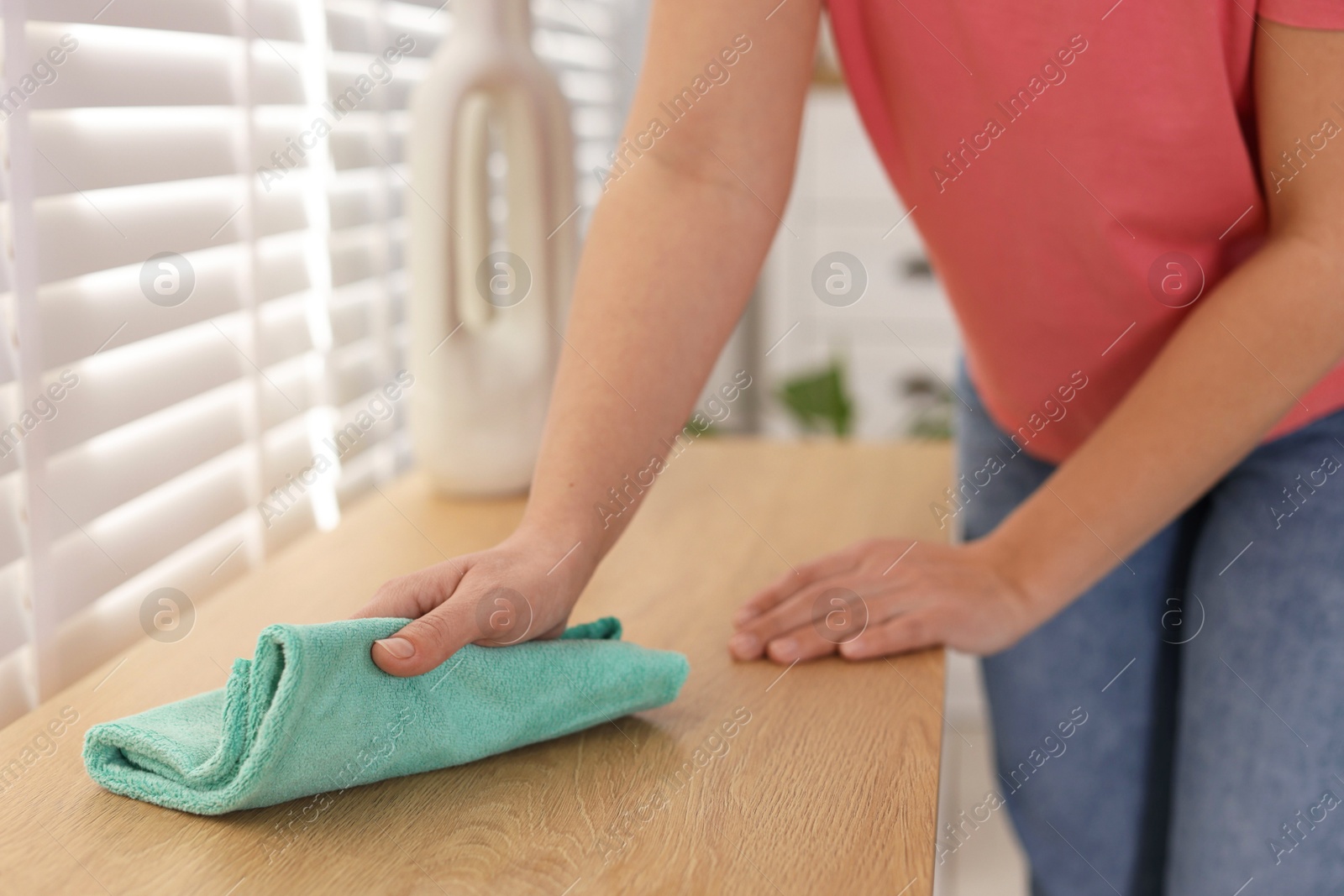 Photo of Woman polishing wooden table with rag at home, closeup