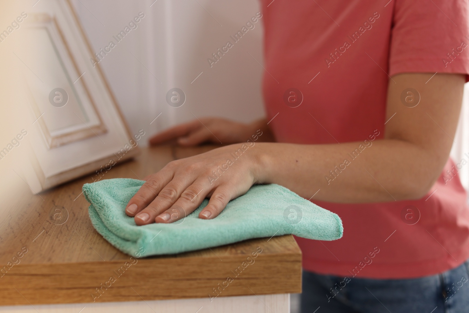 Photo of Woman polishing wooden cabinet with rag at home, closeup