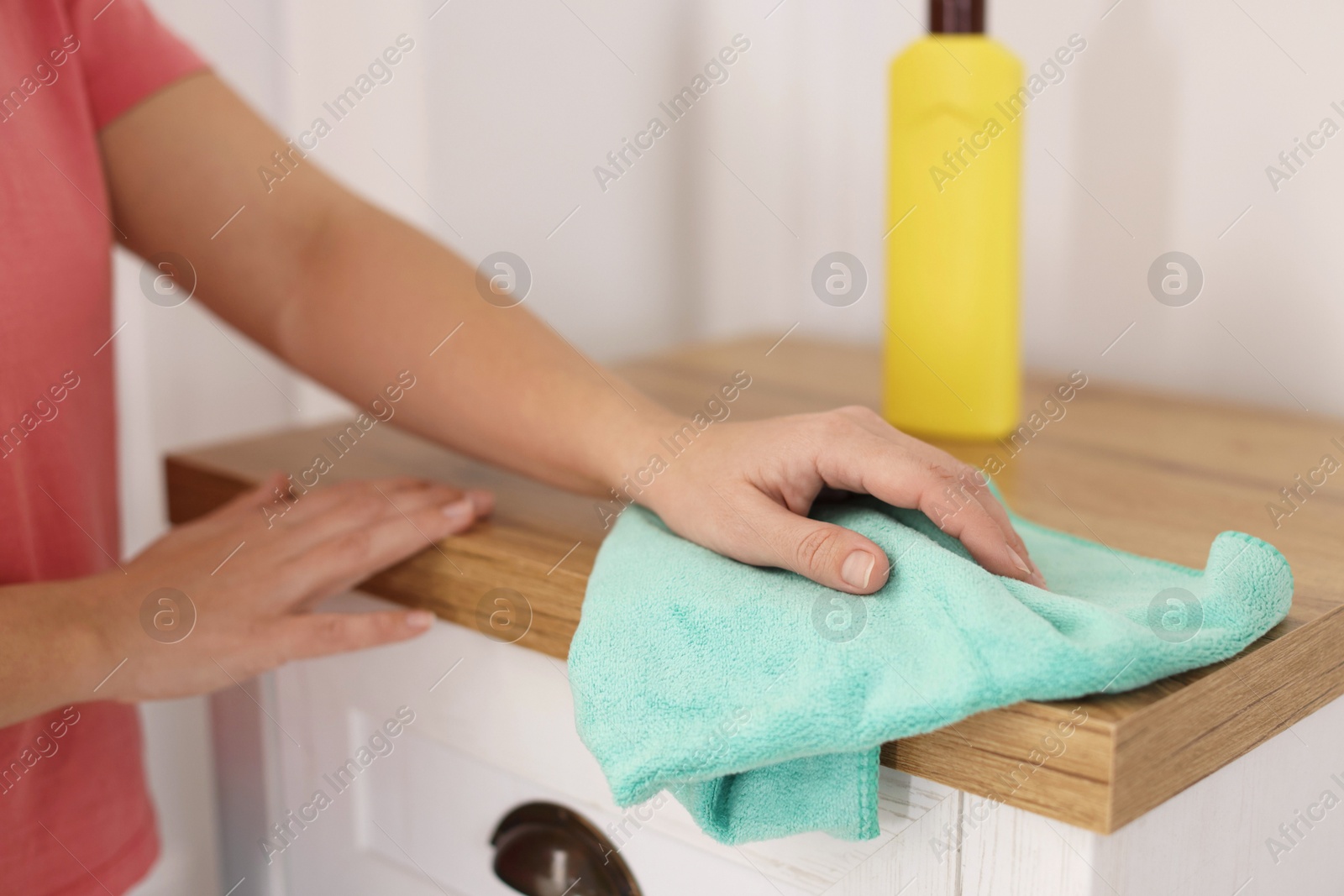 Photo of Woman polishing wooden cabinet with rag at home, closeup