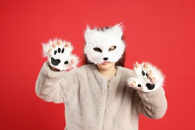 Photo of Quadrobics. Girl wearing cat mask and gloves on red background