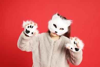 Quadrobics. Girl wearing cat mask and gloves on red background