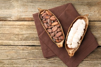 Photo of Cocoa pods with beans on wooden table, top view. Space for text