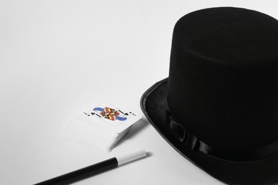 Playing cards, hat and magic wand on light background, closeup. Space for text