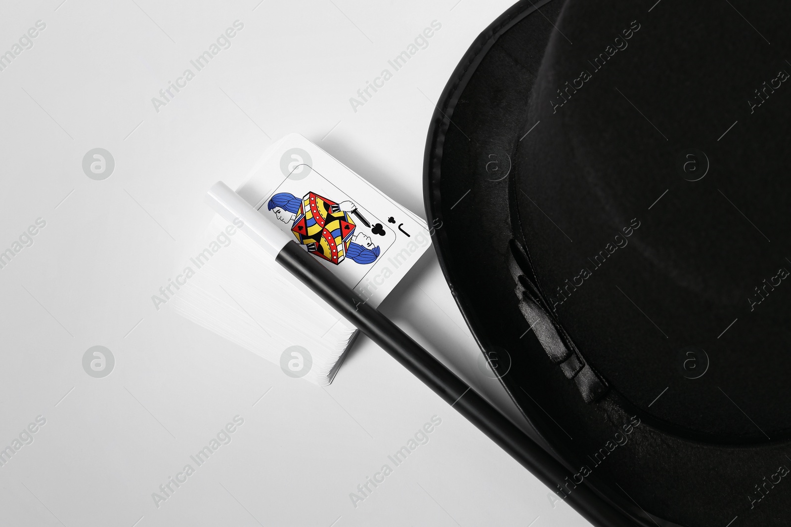 Photo of Playing cards, hat and magic wand on light background, closeup