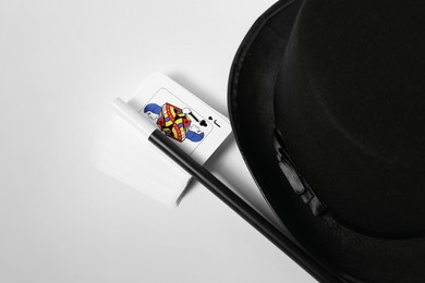 Photo of Playing cards, hat and magic wand on light background, closeup