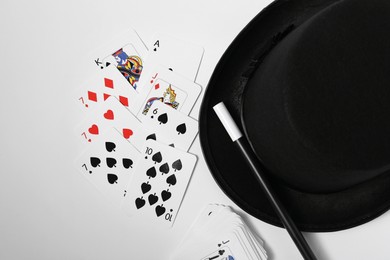 Photo of Playing cards, hat and magic wand on light background, top view